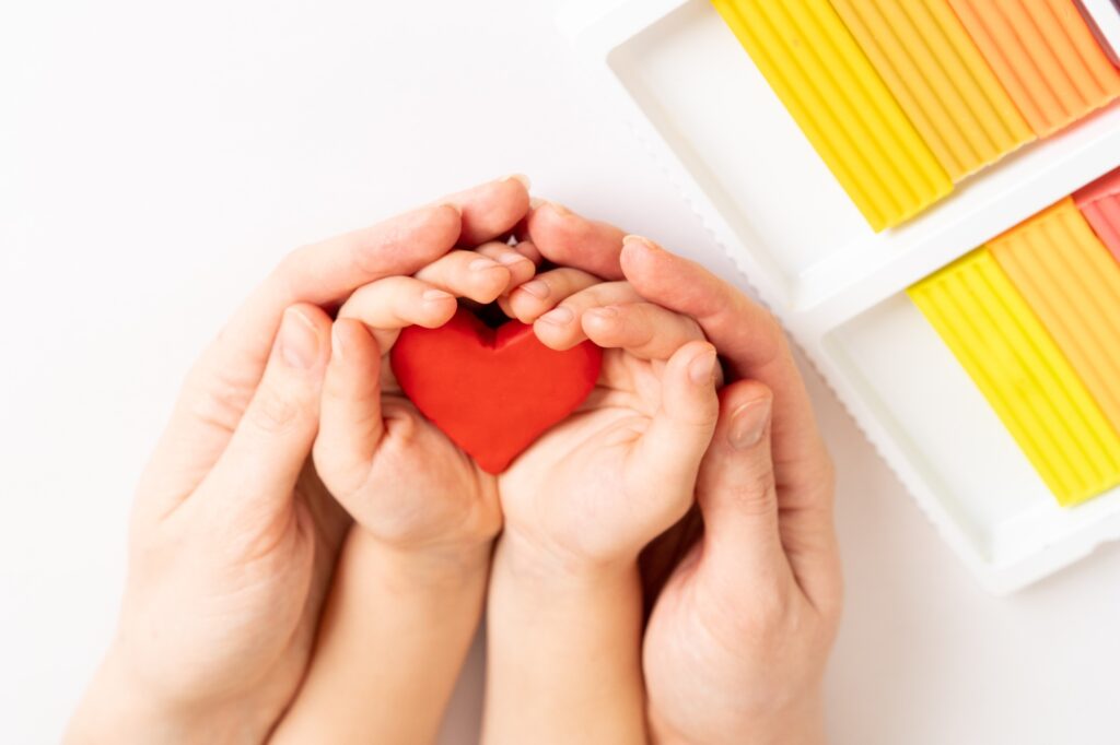 Plasticine heart in the hands of mom and baby